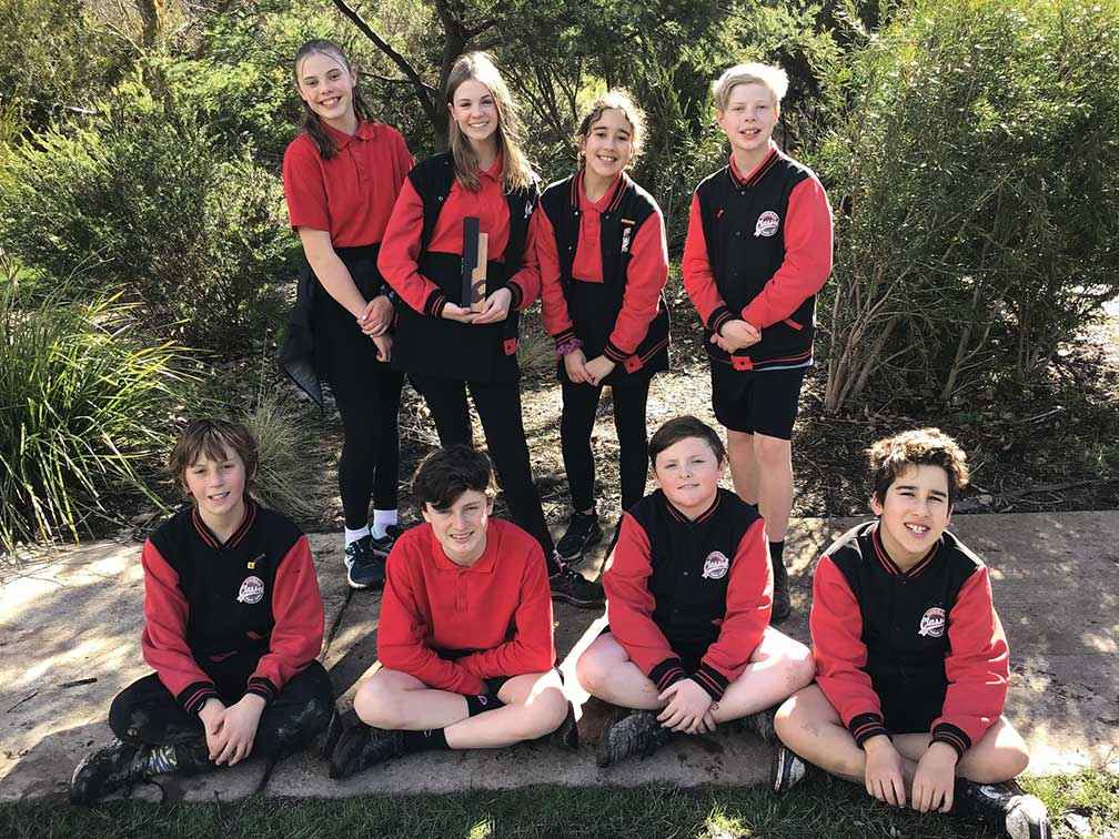 Newham Primary School leaders with the 2021 National Woolworths Junior Landcare Team Award in front of a revegetation site at the school. From left standing, Minty, Tilly, Layla and Riley. From left sitting, Loki, Freddie, Harper and Zayne.