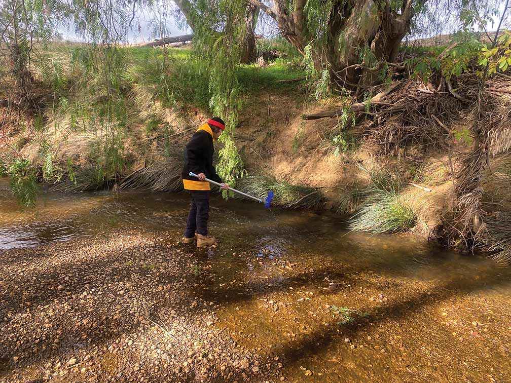 Annalise Varker at Bendigo Creek collecting a sample for water quality testing.